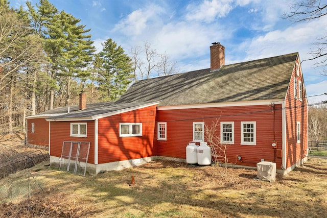 rear view of house featuring roof with shingles and a chimney