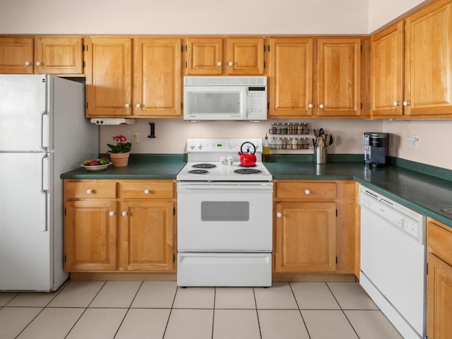 kitchen with light tile patterned floors, dark countertops, brown cabinetry, and white appliances
