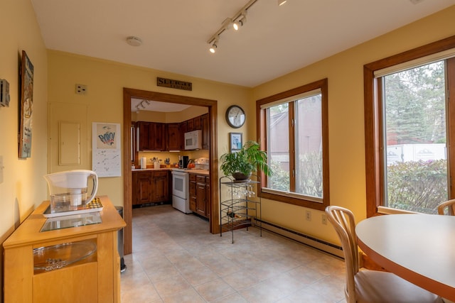 dining area featuring baseboard heating, light tile patterned floors, a healthy amount of sunlight, and track lighting
