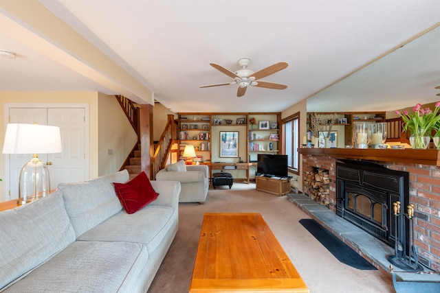 carpeted living area with stairway, a ceiling fan, and a brick fireplace