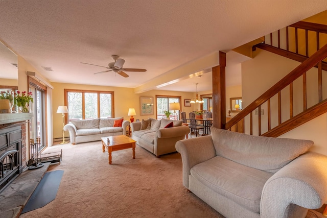 carpeted living room with a wood stove, ceiling fan with notable chandelier, stairs, and a textured ceiling