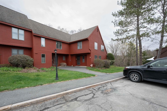 exterior space with a shingled roof and a yard