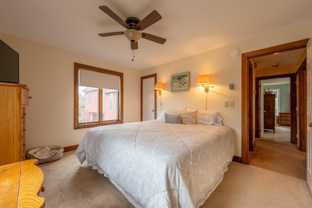 bedroom with a ceiling fan, light carpet, and baseboards