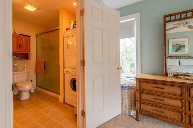 full bathroom featuring stacked washing maching and dryer, a stall shower, and toilet