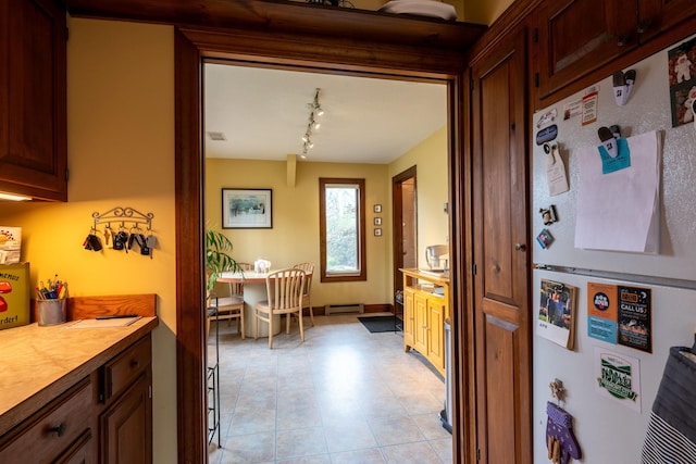 kitchen featuring light countertops, rail lighting, a baseboard radiator, and freestanding refrigerator