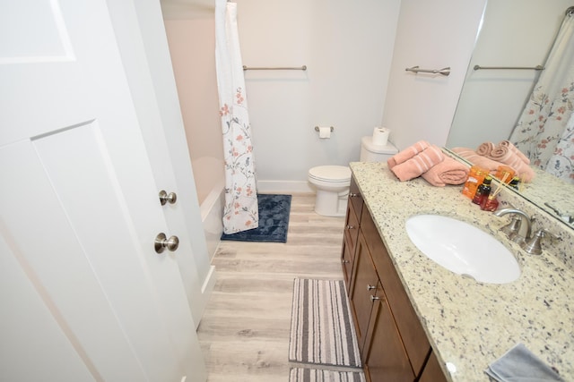 full bathroom with baseboards, shower / bath combo with shower curtain, toilet, wood finished floors, and vanity