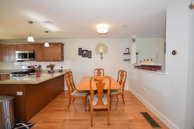 dining room featuring visible vents, light wood-style flooring, and baseboards