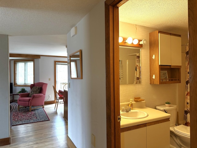 bathroom with toilet, vanity, a textured ceiling, and wood finished floors