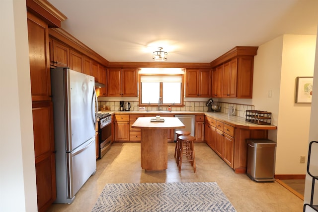 kitchen featuring appliances with stainless steel finishes, a center island, light countertops, and backsplash