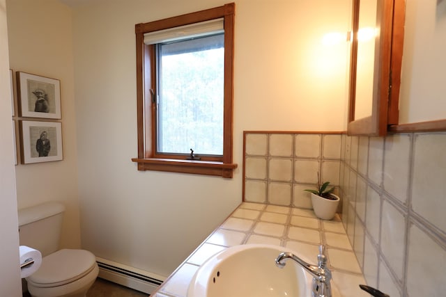 bathroom featuring a baseboard radiator, toilet, tasteful backsplash, and a sink