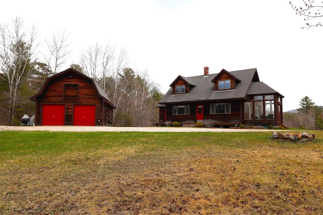 view of front of house with a chimney, a barn, a garage, driveway, and a front lawn