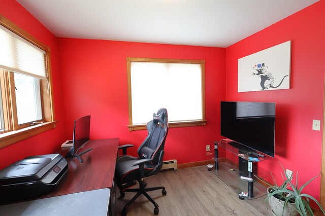 office area featuring baseboard heating, a wealth of natural light, wood finished floors, and baseboards
