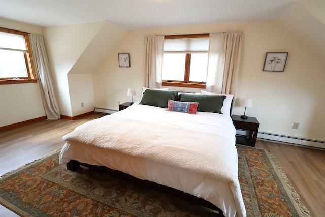 bedroom featuring multiple windows, baseboard heating, and wood finished floors