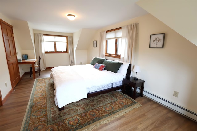 bedroom featuring baseboards, wood finished floors, and a baseboard heating unit