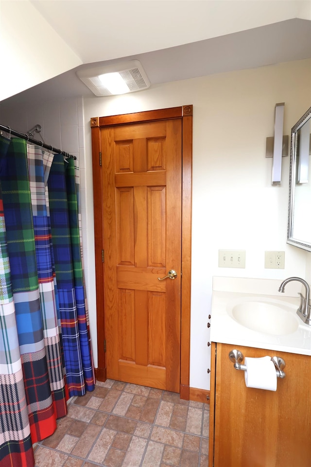 full bathroom featuring stone finish flooring, vanity, a shower with curtain, and baseboards