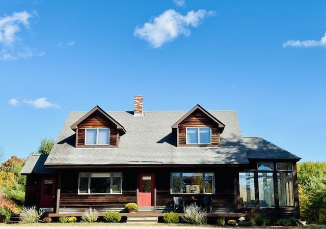 cabin with a chimney, covered porch, and a sunroom
