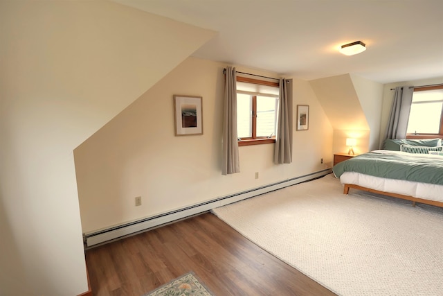 bedroom with wood finished floors and a baseboard heating unit