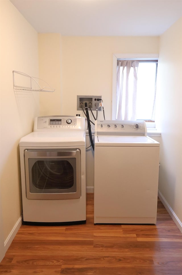 clothes washing area featuring light wood-style floors, washer and clothes dryer, laundry area, and baseboards