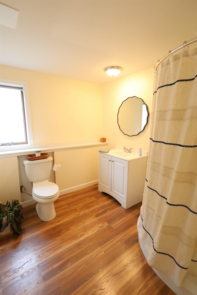 bathroom with vanity, curtained shower, toilet, baseboards, and wood finished floors