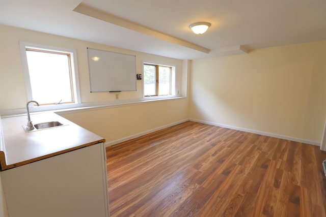 empty room with wood finished floors, baseboards, and a sink