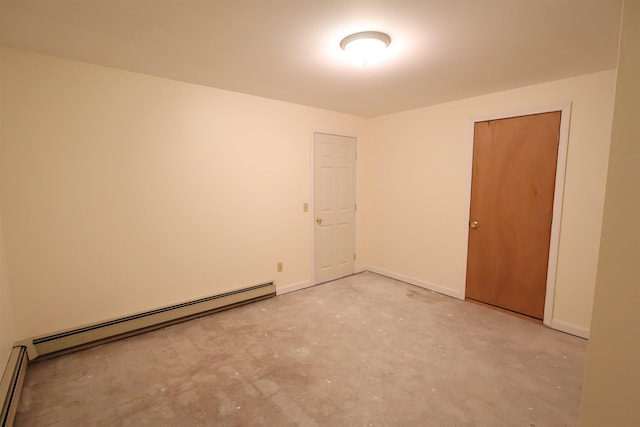 spare room featuring baseboards, a baseboard heating unit, and concrete floors