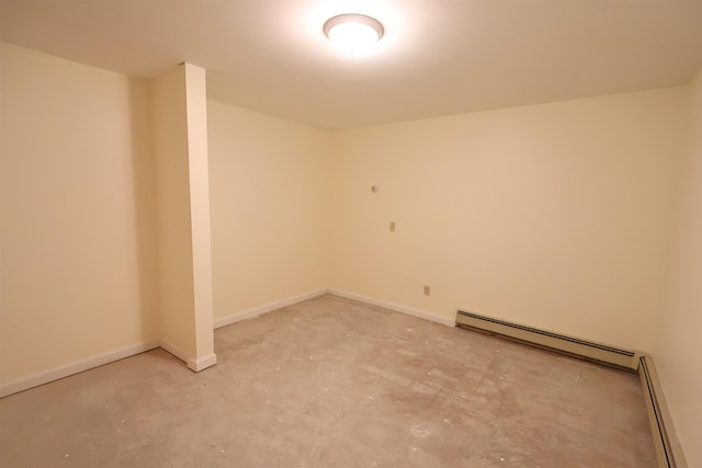 spare room with unfinished concrete flooring, a baseboard heating unit, and baseboards