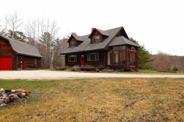 view of front of property featuring a garage, a porch, an outdoor structure, and a front lawn
