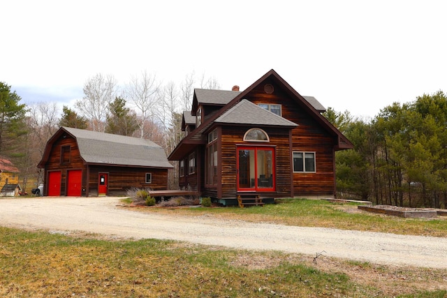 log-style house with a garage, a chimney, an outdoor structure, and roof with shingles