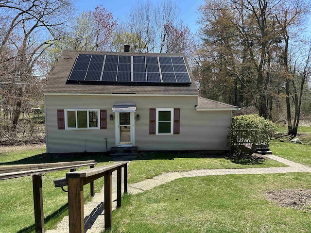 bungalow-style house with a front yard, solar panels, a shingled roof, and entry steps