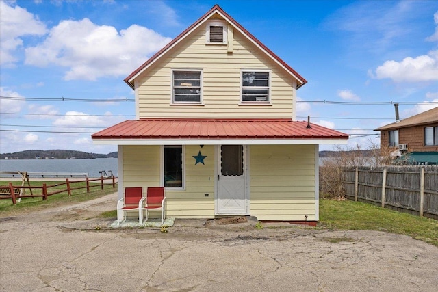 rear view of house featuring covered porch and fence