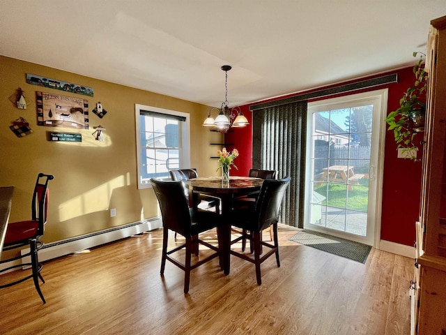 dining space with baseboards, light wood finished floors, a chandelier, and a wealth of natural light