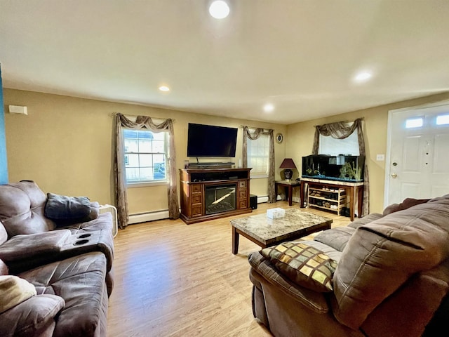 living area featuring recessed lighting, light wood-style floors, a glass covered fireplace, and baseboard heating