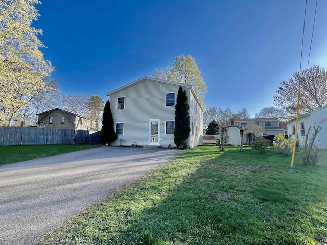view of home's exterior featuring fence, aphalt driveway, and a lawn
