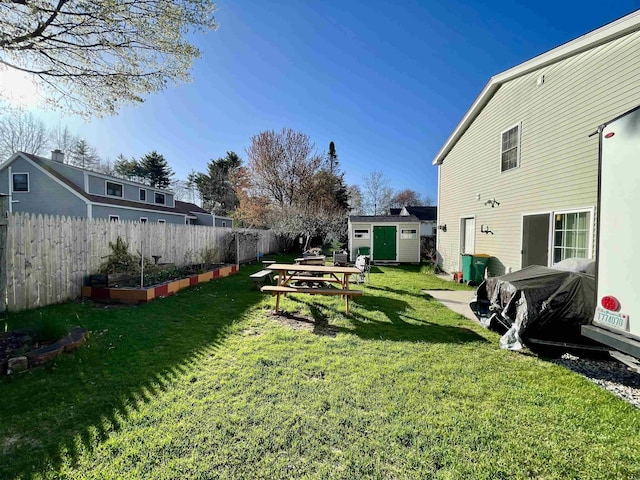 view of yard featuring fence, a garden, an outdoor structure, and a storage unit