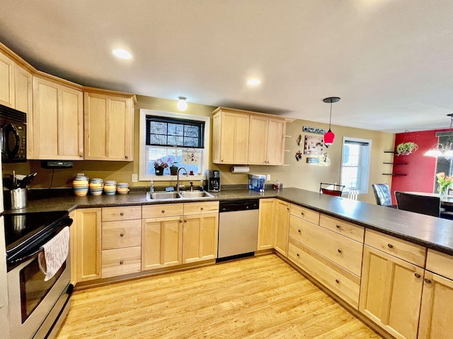 kitchen featuring a sink, light brown cabinets, light wood-type flooring, dark countertops, and appliances with stainless steel finishes