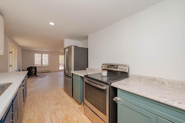 kitchen with green cabinetry, a wood stove, appliances with stainless steel finishes, and light countertops
