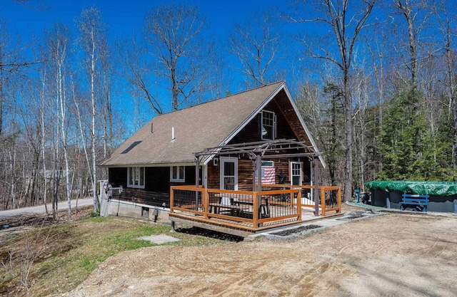 rear view of house featuring roof with shingles and a deck