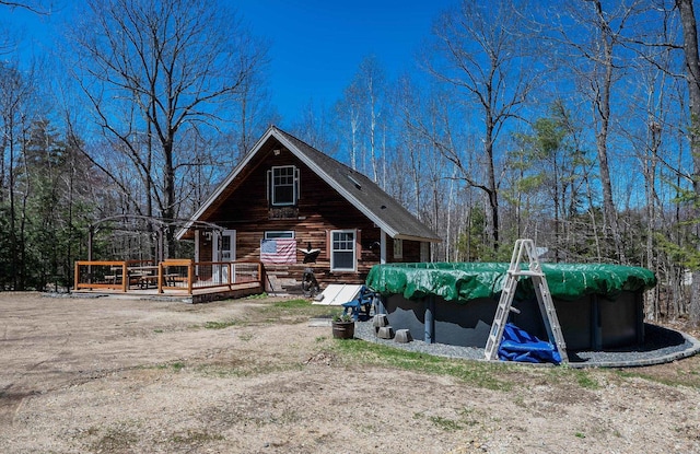 rear view of house with a covered pool and a wooden deck