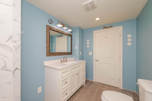 bathroom featuring visible vents, toilet, wood finish floors, and vanity