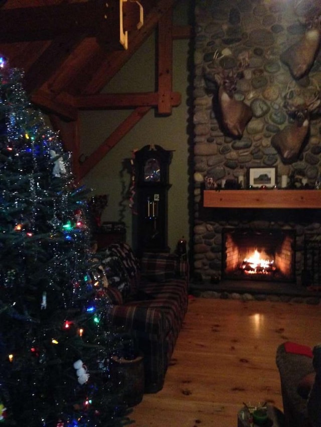 living room with wood finished floors and a stone fireplace