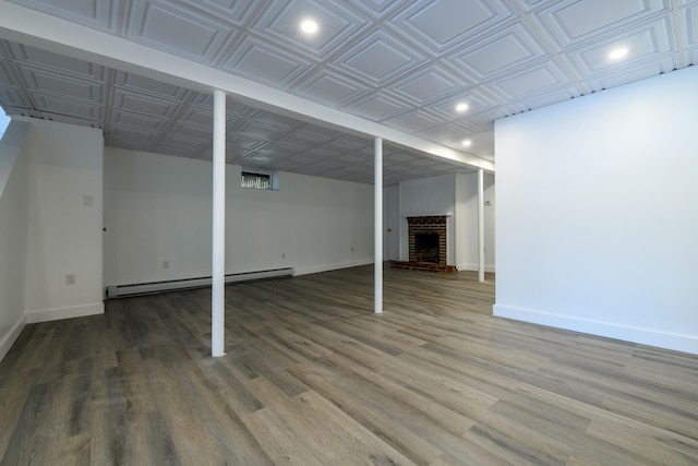 finished basement with a baseboard heating unit, recessed lighting, an ornate ceiling, baseboards, and wood finished floors