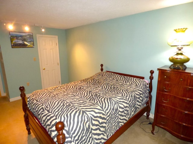carpeted bedroom featuring track lighting and baseboards