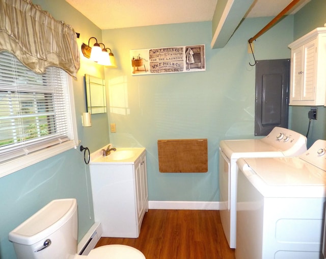 bathroom featuring wood finished floors, a baseboard radiator, toilet, electric panel, and washing machine and dryer