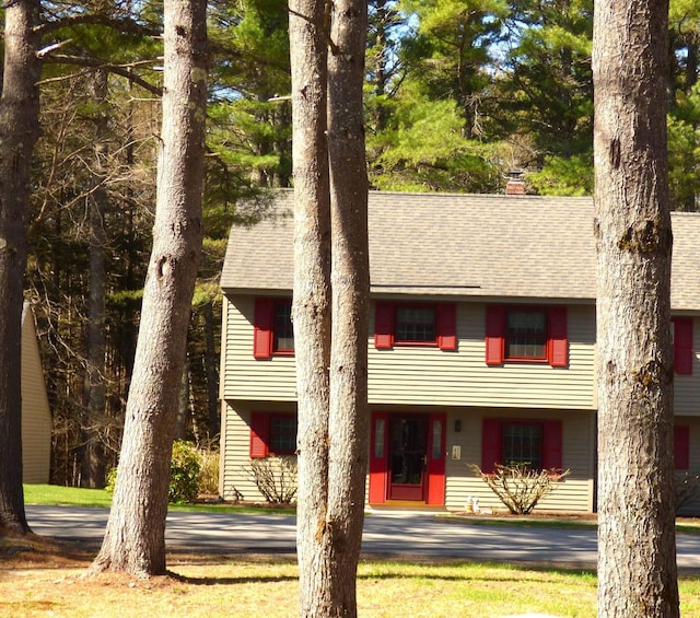 view of front of house featuring a chimney and a shingled roof