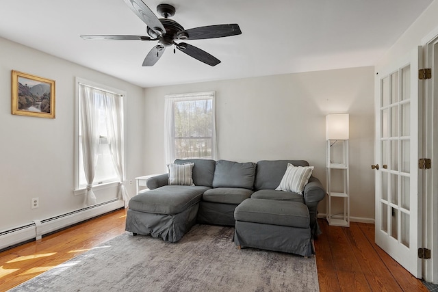 living area with hardwood / wood-style floors, a ceiling fan, and a baseboard radiator