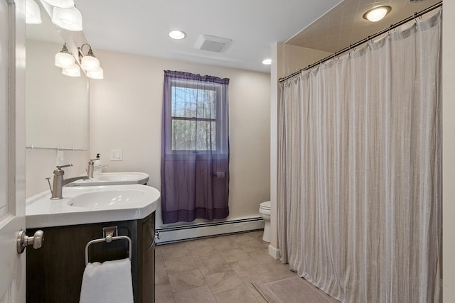 bathroom with a sink, double vanity, visible vents, a baseboard heating unit, and toilet