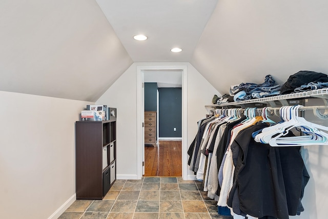 spacious closet featuring stone finish flooring and vaulted ceiling
