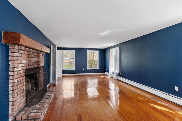 unfurnished living room with hardwood / wood-style floors, baseboards, a baseboard heating unit, and a fireplace