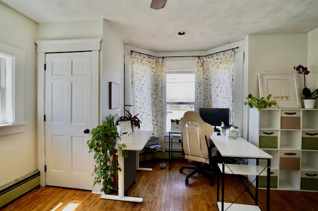 office with a ceiling fan, a baseboard heating unit, and wood finished floors