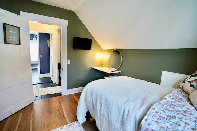 bedroom with baseboards, wood finished floors, and lofted ceiling